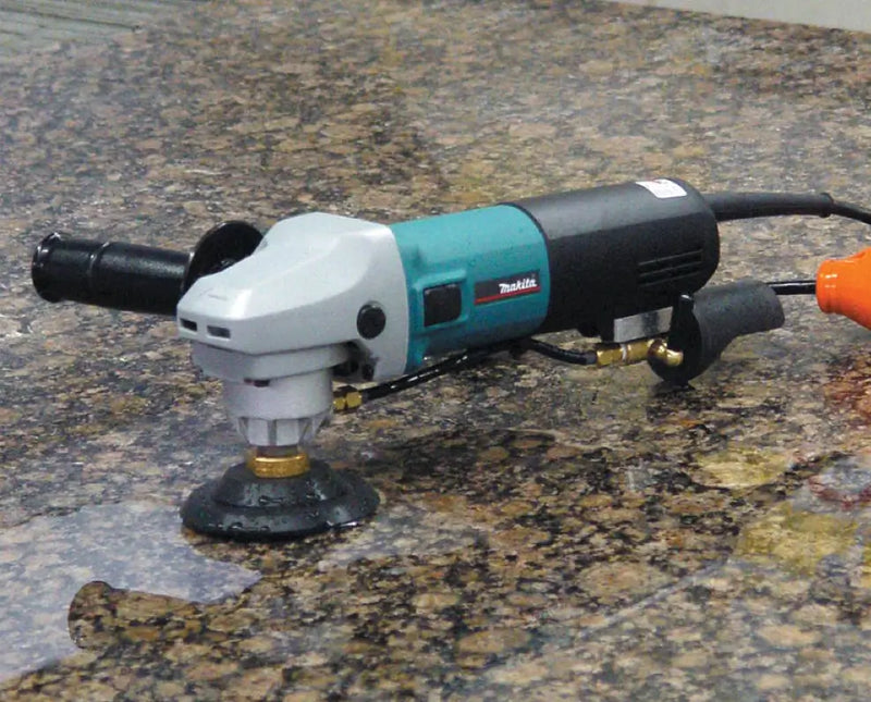 Electric Makita angle grinder placed on a polished granite surface.

